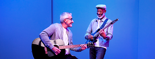 Image of two senior men playing guitar together